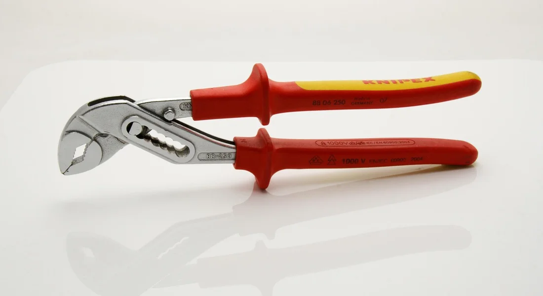 Red-handled adjustable wrench lying on a white surface