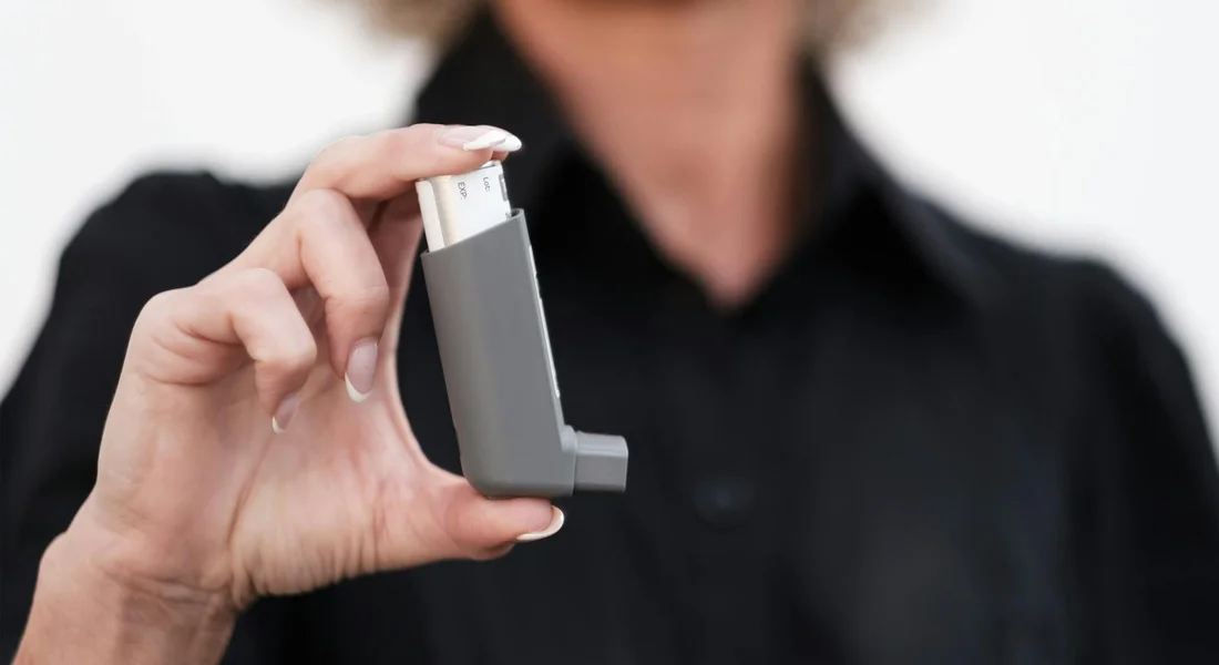 Close-up of a person in a dark shirt holding a small gray backflow preventer test device
