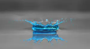 Blue water splash with reflection on a gray surface