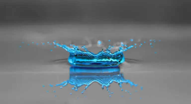 Blue water splash with reflection on a gray surface