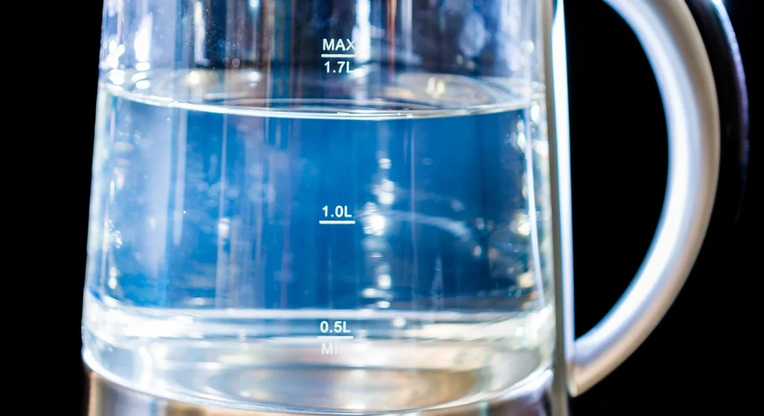 Close-up of a transparent measuring container with blue liquid and measurement markings (0.5L, 1.0L, 1.7L).
