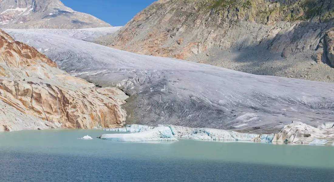 Glacier-fed lake with mountains and rocky slopes in the background, illustrating water source context for home treatment choices.