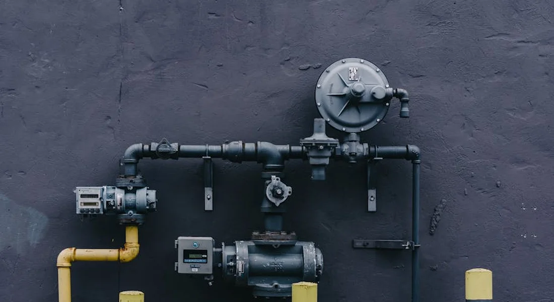 Close-up of wall-mounted home water system with pipes, valves, and a pressure gauge.