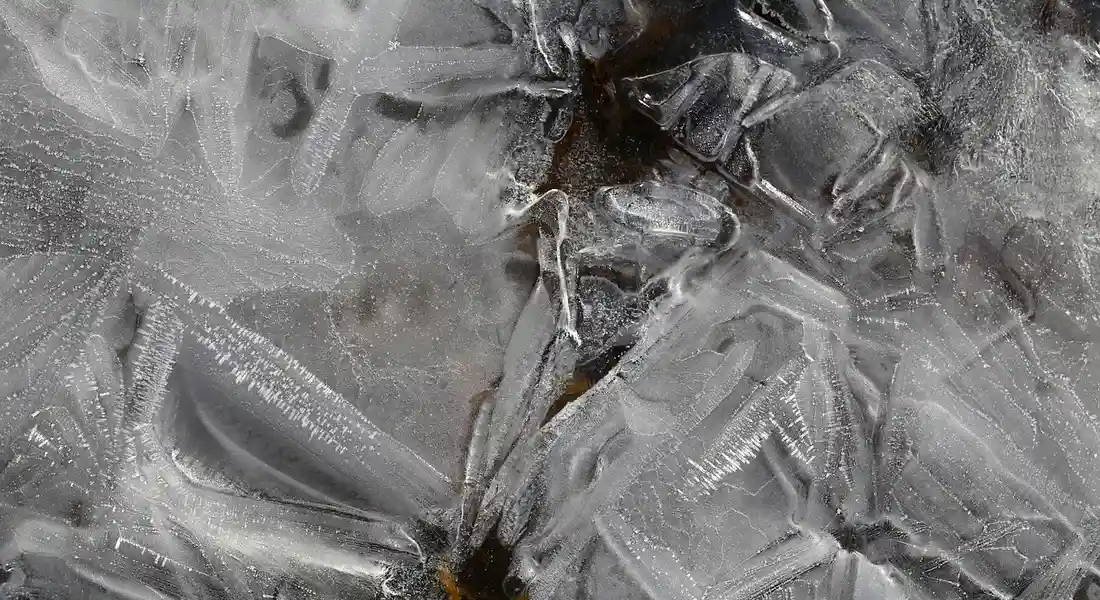 Close-up of ice crystals on a frosty surface, illustrating ice maker and water line connections.