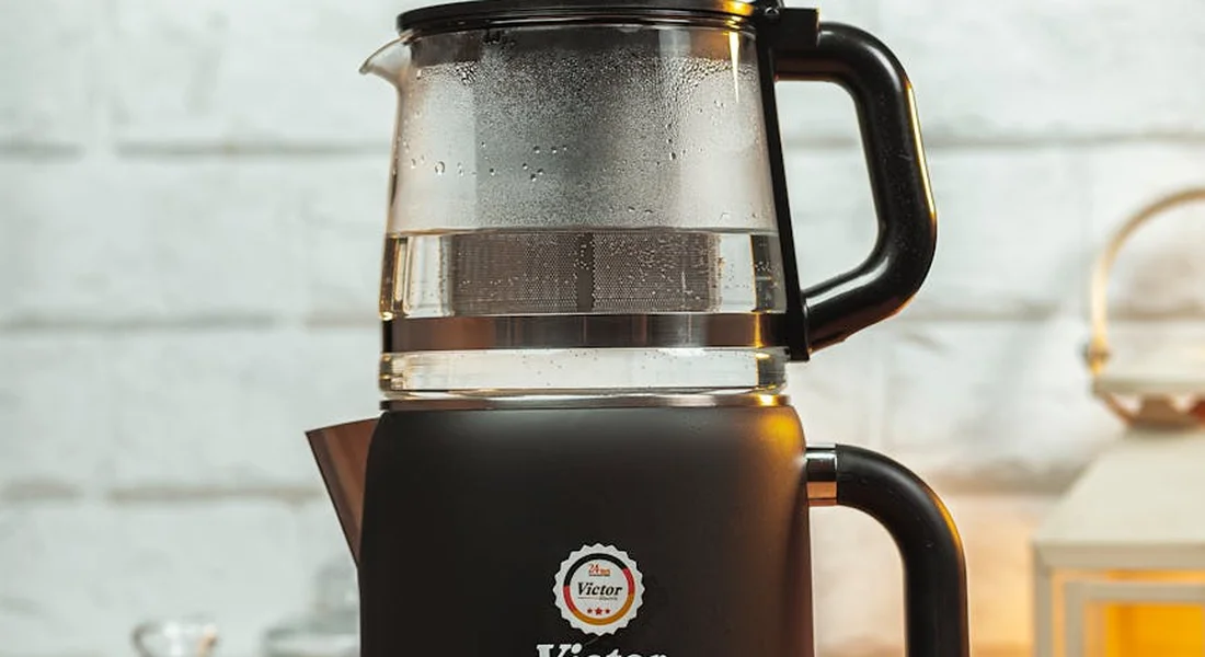 Black countertop blender with a glass pitcher and handle, placed on a light kitchen surface.