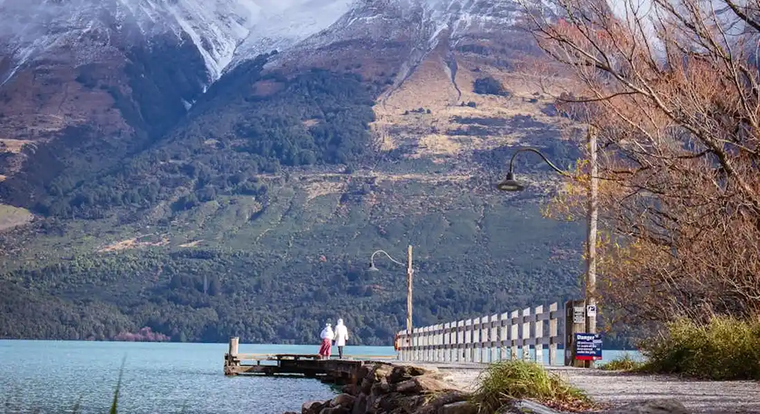 A wooden pier extending into a calm lake with rugged mountains in the background, conveying a cold-climate setting ideal for year-round heat pump water heater maintenance.