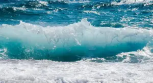 Ocean waves crashing on a shoreline with turquoise water and white foam.