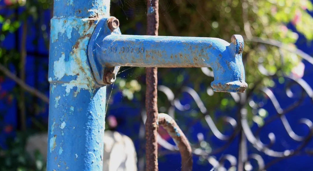 Blue outdoor hand-operated well pump with weathered paint and rust, illustrating pump selection for home water systems.