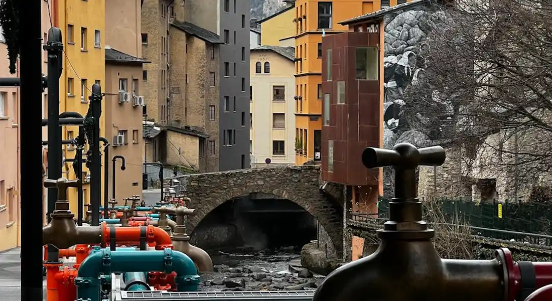Exterior plumbing valves and multicolored pipes with a historic town backdrop