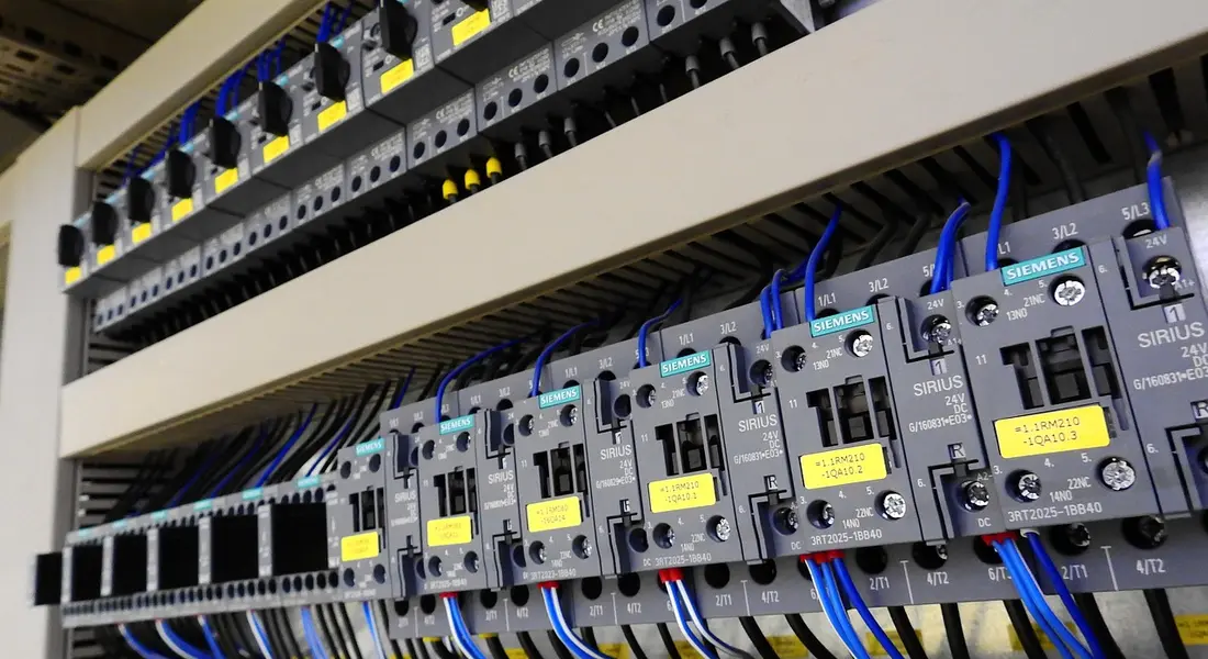 Close-up of an electrical service panel with multiple circuit breakers and blue wires connected to a row of breakers