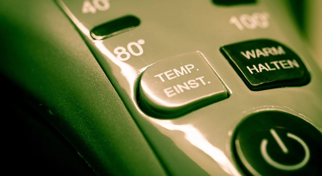 Close-up of a metallic control panel with a rounded button labeled TEMP. EINST., reflecting light.