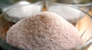 Close-up of pink Himalayan salt crystals in a glass bowl.