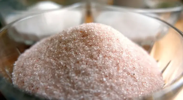 Close-up of pink Himalayan salt crystals in a glass bowl.