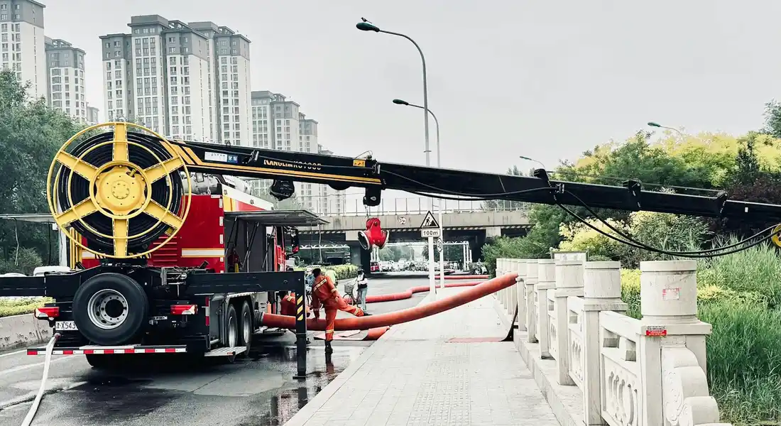 A pipe thawing machine with a large reel and orange hoses on a city street, with workers nearby preparing to thaw or inspect water pipes.