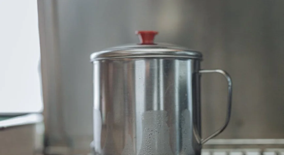 Stainless steel pot with a red knob on its lid on a stovetop, ready for a heating demonstration.
