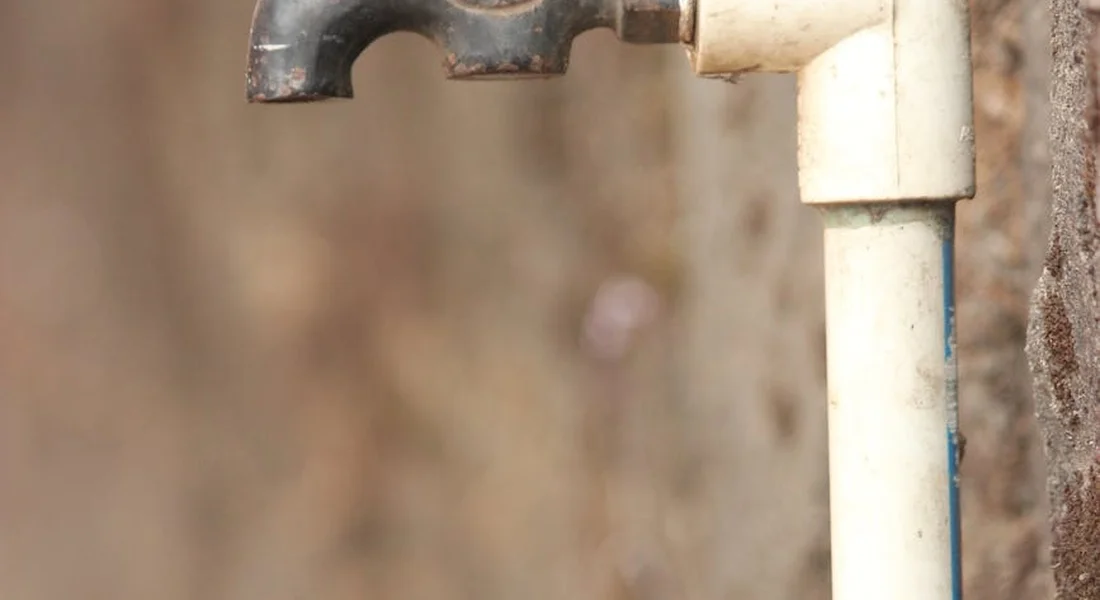 Close-up of a home water supply pipe with visible mineral buildup and a corroded joint