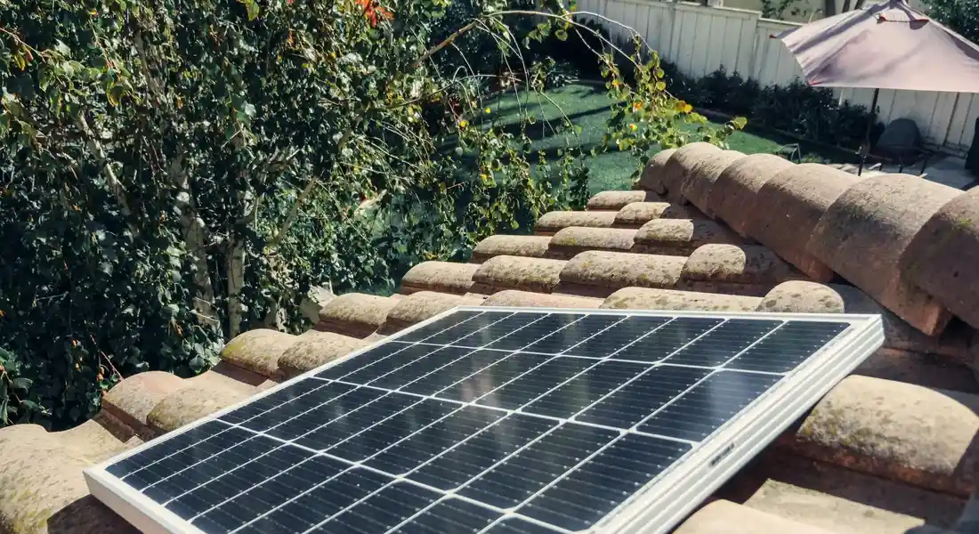 Rooftop solar panel on a tiled roof with greenery in the background