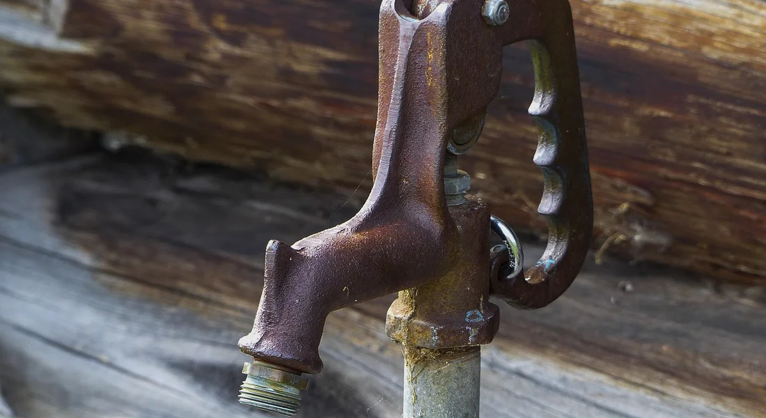 Rusty outdoor spigot attached to a wooden surface, ready for replacement.