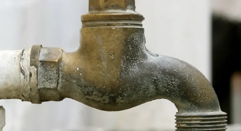Close-up of a weathered outdoor water spigot with a threaded outlet used for filling RV freshwater tanks.