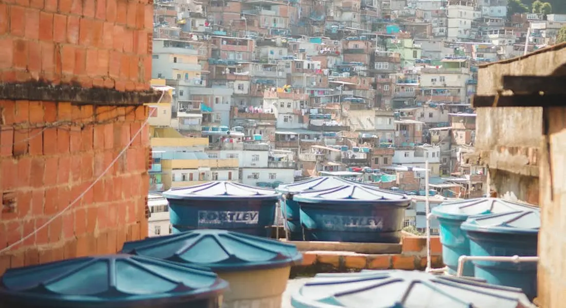 Rooftop water storage tanks on a densely built hillside neighborhood, representing water storage and supply management.