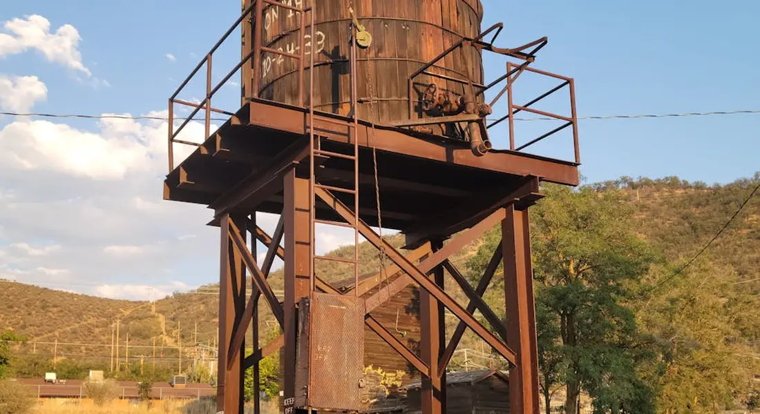 Rusty elevated water storage tank on a metal frame in a desert landscape