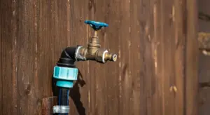 Outdoor RV water faucet with shut-off valve and hose connector mounted on wooden siding