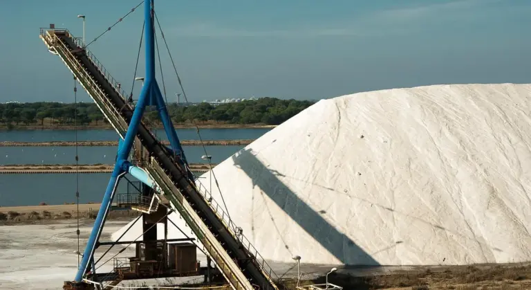 Industrial salt pile with a conveyor system at a processing site.