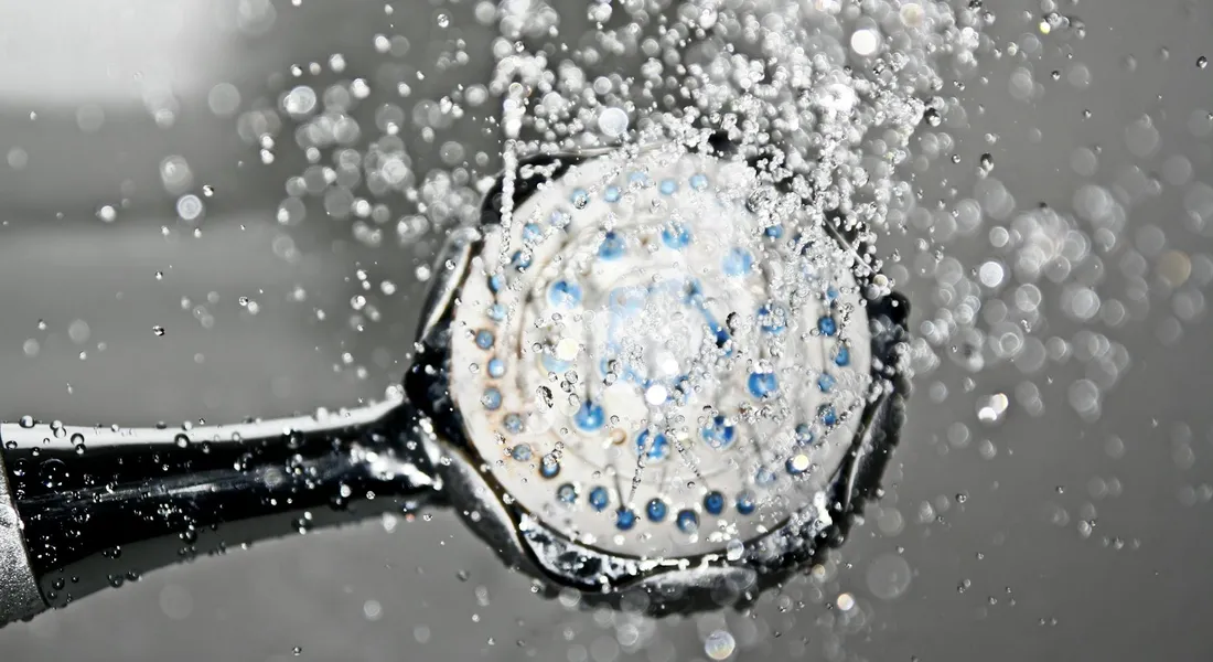 Close-up of a showerhead with water droplets spraying outward