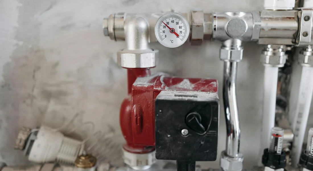 Close-up of a submersible water pump with pressure gauge and plumbing connections