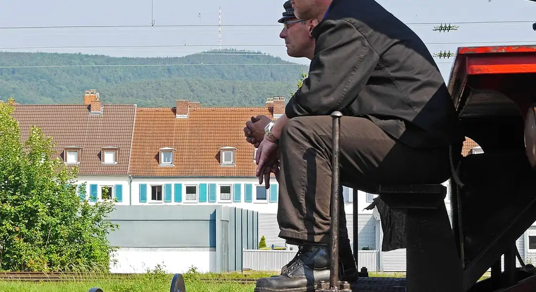 A person in workwear crouches beside a pickup truck in a suburban area, illustrating a real-world setting for home energy efficiency discussions.