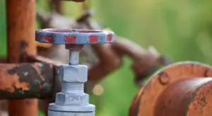 Close-up of a metal valve on a rusted pipe, illustrating plumbing hardware
