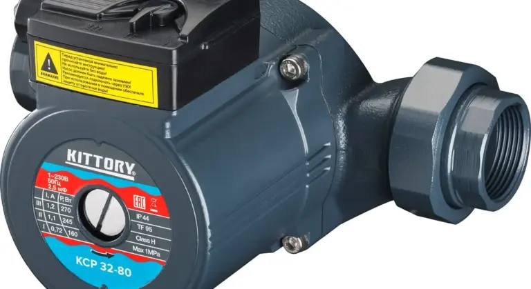 Close-up of a blue sump pump with threaded outlet and yellow warning label