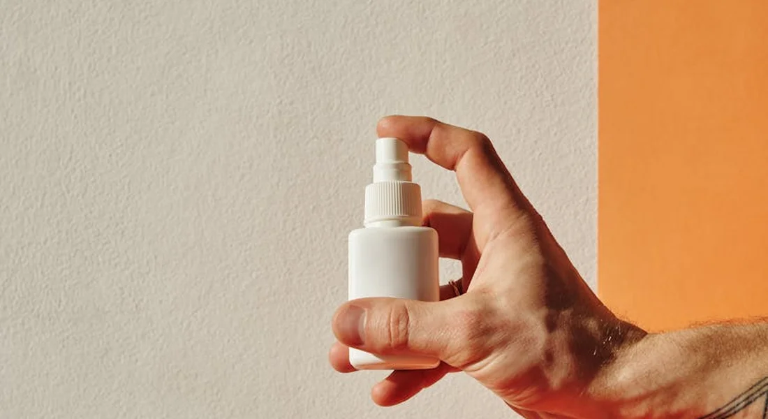 Hand gripping a spray bottle of cleaning solution used for sump pump maintenance