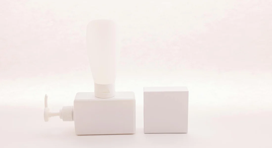 A white, compact sump pump component with a vertical discharge outlet and a square base.