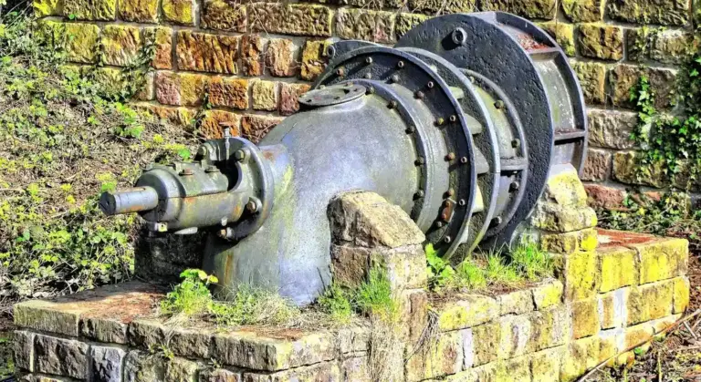 Outdoor industrial sump pump mounted on a brick pedestal with a large flange and piping