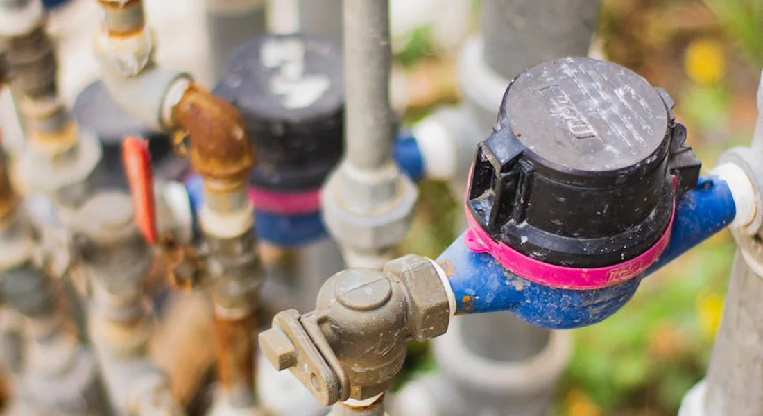 Close-up of plumbing valves and a water meter, illustrating components involved in sump pump systems.