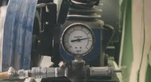 Close-up view of a sump pump with piping and a pressure gauge, highlighting venting components and drainage connections.