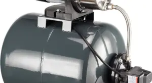 Gray submersible sump pump with float switch and discharge hose mounted in a sump basin.