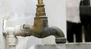 Close-up of a weathered outdoor water valve with a threaded outlet ready for a temporary cap