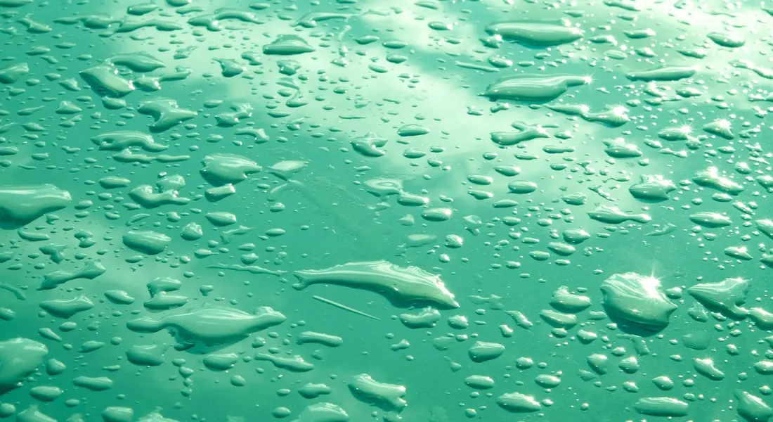 Close-up of water droplets on a teal surface