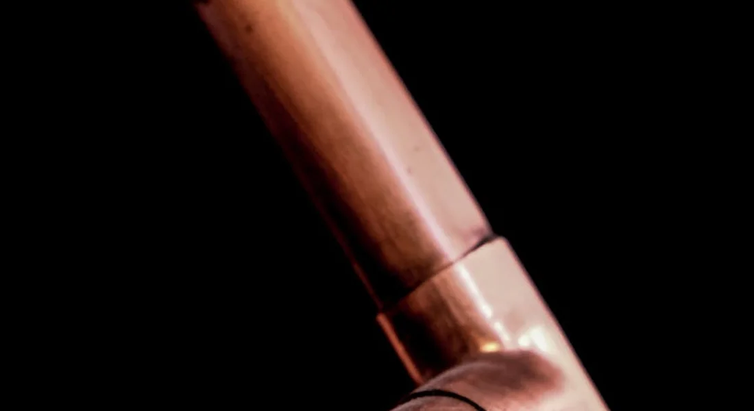 Close-up of a copper pipe elbow and fittings against a dark background