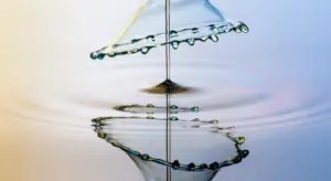 Close-up of a water droplet creating ripples on a calm water surface.