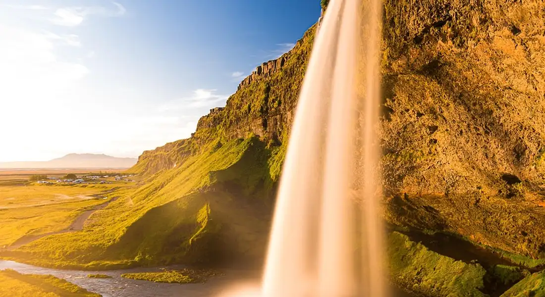 A sunlit waterfall cascading down a rocky cliff, symbolizing clear, flowing water