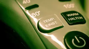 Close-up of a water heater thermostat control panel showing a temperature setting button and a power/standby button