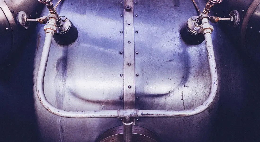 Close-up of a metal water heater with connected pipes and fittings, illustrating a typical installation.