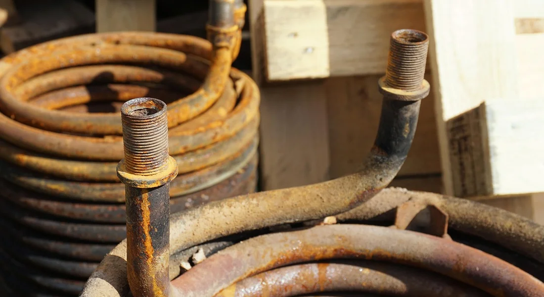 Close-up of rusted water heater pipes and fittings in a utility area.