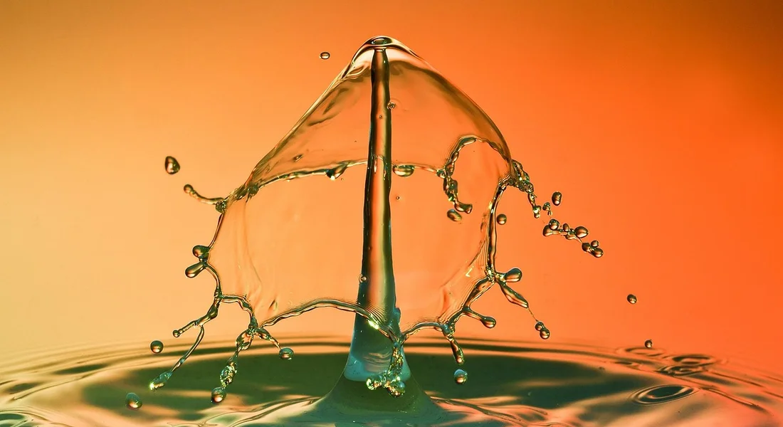 Close-up of a water droplet splashing on an orange background, illustrating the pressure relief valve in a water heater