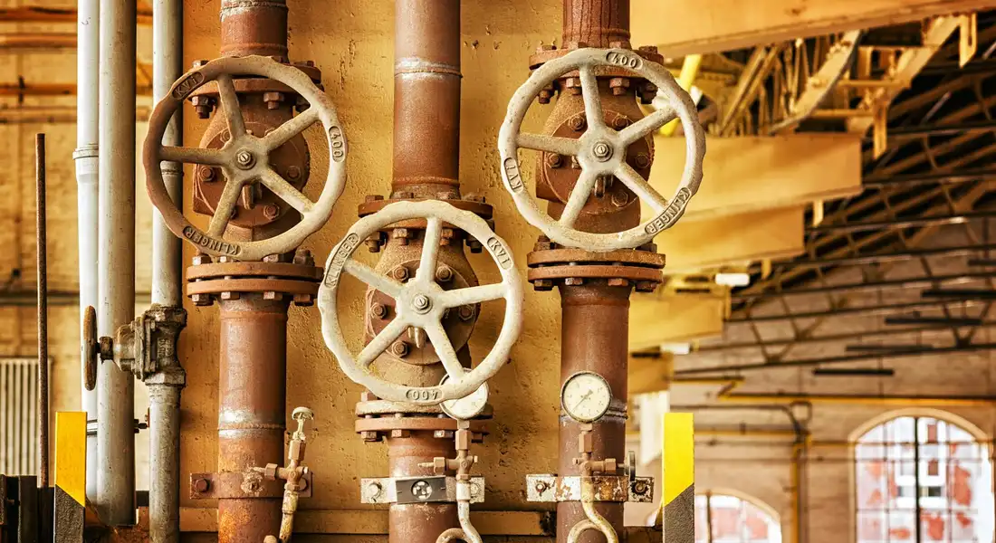 Industrial water piping with wheel valves, illustrating potential pressure tank issues.