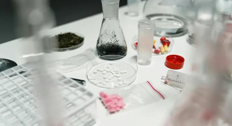 Lab bench with purification tablets, a Petri dish, beakers, and glassware used to study water treatment tablets.