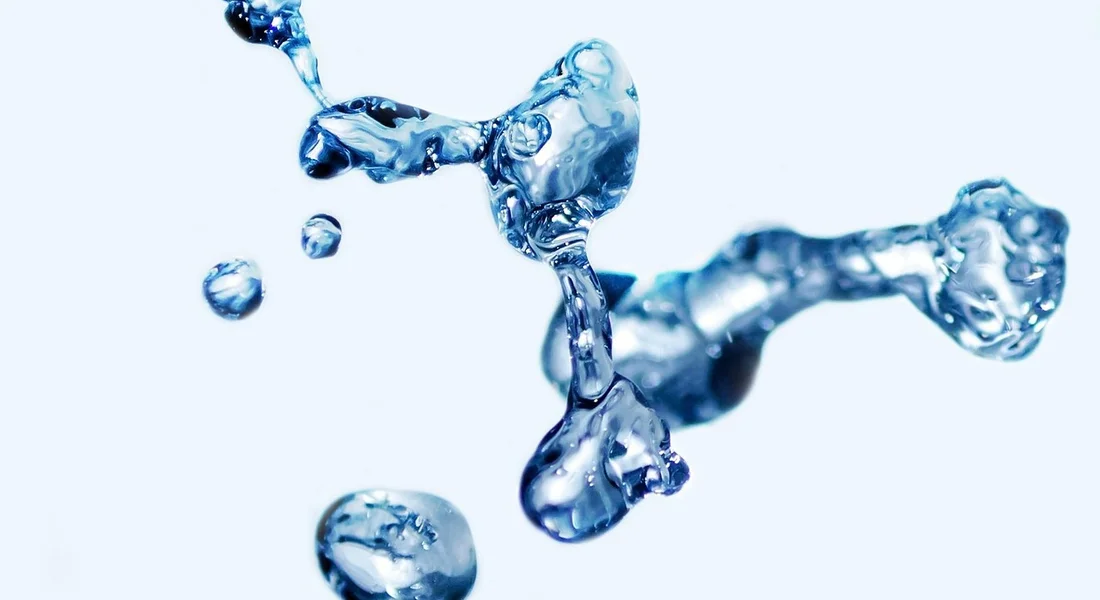 Close-up of water splashes and droplets against a pale blue background.